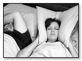 Woman holding pillow over ears to block sound of husband snoring and sleep apnea